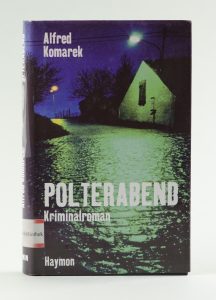 Okładka książki Alfreda Komarka pt. Polterabend przedstawiająca brukowaną drogę wiodącą przez miasteczko.