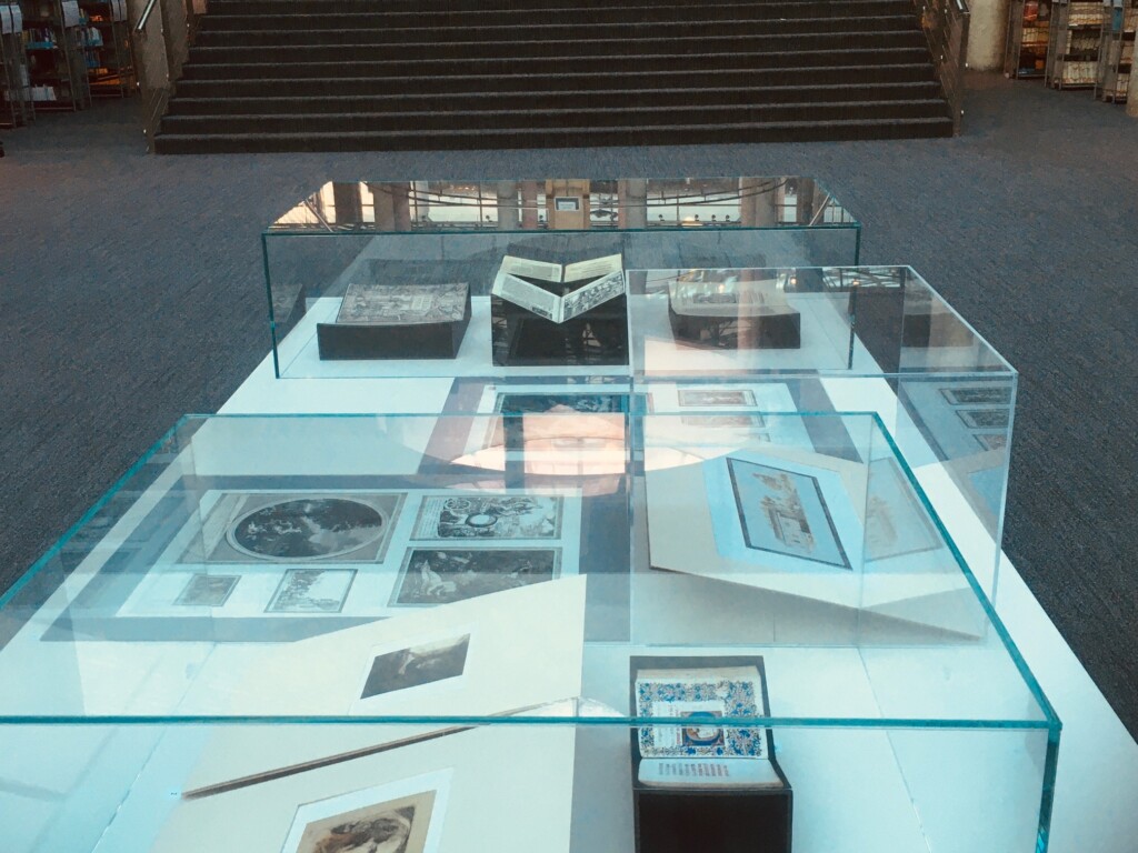 Szklana gablota wystawowa z książkami w środku, w tle schody.