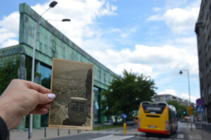 Zdjęcie trzymanej w ręku pocztówki z widokiem na kolejkę na Gubałówkę. W tle widać przejeżdżający autobus oraz fasadę BUW.