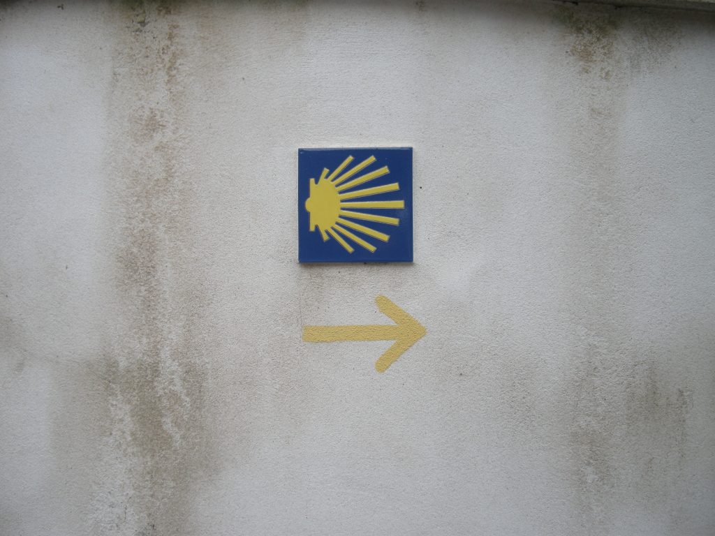 Symbol żółtej muszli na niebieskim tle, charakterystyczny dla dróg św. Jakuba