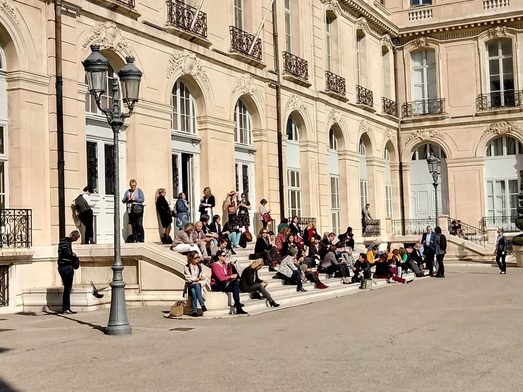 Zdjęcie ludzi siedzących na schodach zabytkowego pałacu