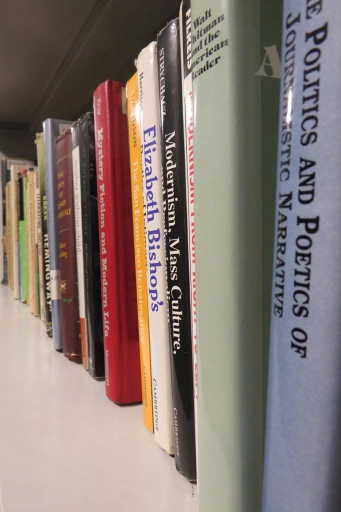 Zdjęcie, zbliżenie na grzbiety anglojęzycznych książek na półce bibliotecznego regału.