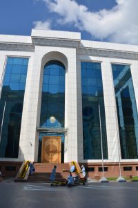 Zdjęcie monumentalnego wejście do biblioteki. Drewniane drzwi są osadzone fasadzie budynku z białego kamienia i szkła.