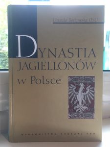 Okładka książki "Dynastia Jagiellonów w Polsce". Na okładce niewielka ilustracja z białym orłem ułożonym jak w godle Polski