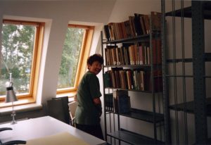 Zdjęcie pokazujące zapełnianie księgozbiorem podręcznym regału w pracowni bibliotecznej.