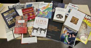 Zdjęcie okładek kilkunastu książek rozłożonych na stole. Prezentacja różnorodności zbiorów Biblioteki Iberystyki.