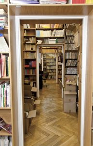 Zdjęcie amfilady z widokiem przez otwory drzwiowe na kolejne pomieszczenia magazynów bibliotecznych szczelnie zastawionych książkami.