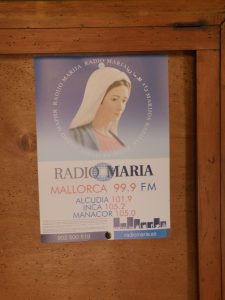 Zdjęcie zawieszonego na szafie plakatu z informacją o częstotliwościach Radia Maryja w Hiszpanii.
