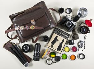 Torba , stary aparat fotograficzny, statyw, filtry do aparatu, obiektywy, światłomierz, rolka filmu i książka