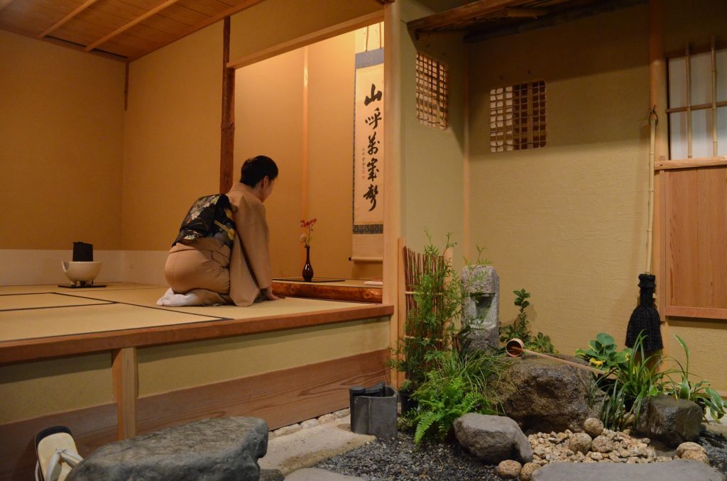Zdjęcie kobiety w tradycyjnym japońskim stroju klęczącej w drewnianym pomieszczeniu