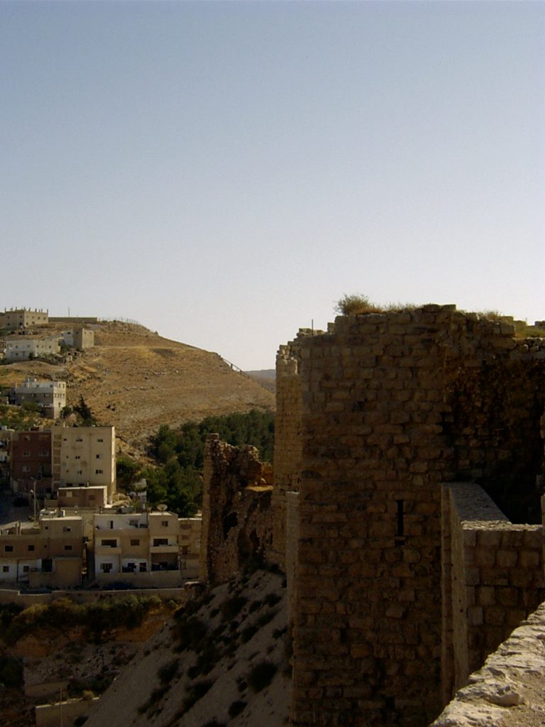 Fragment starych murów, w tle budynki mieszkalne na wzgórzach
