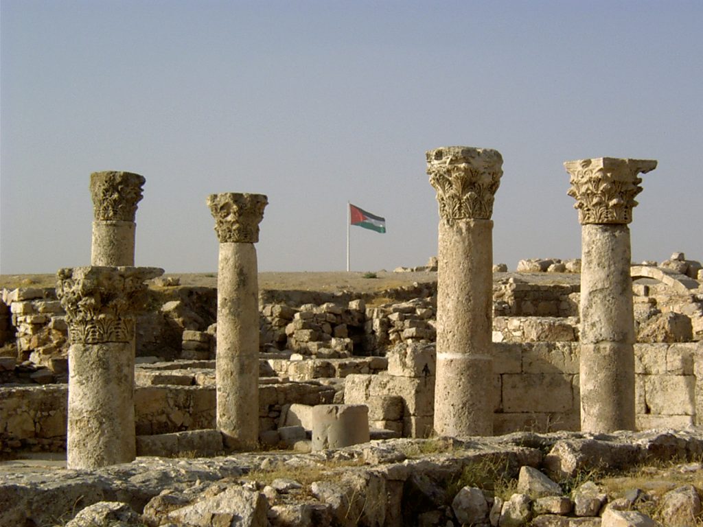 Ruiny - kolumny i fragmenty murów. W tle flaga Jordani