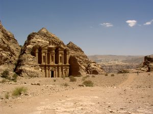Wykuty w skale grobowiec, fragment pustyni i niebo z małymi obłokami