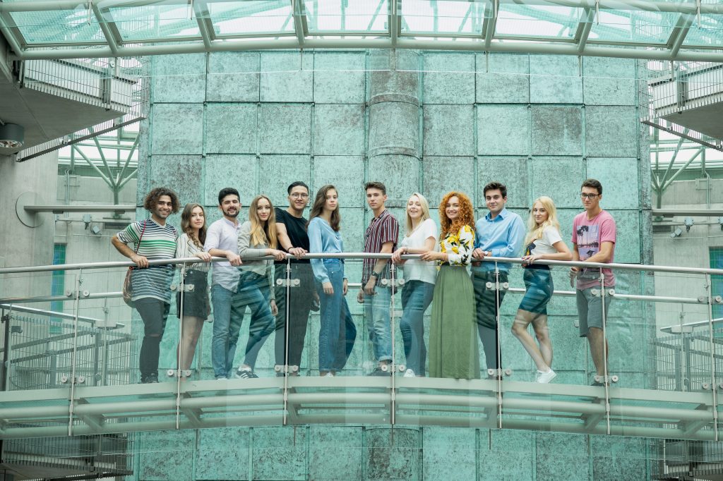 grupa młodych osób zróżnicowanych etnicznie stoi na mostku, studenci zagraniczni, Biblioteka Uniwersytecka w Warszawie