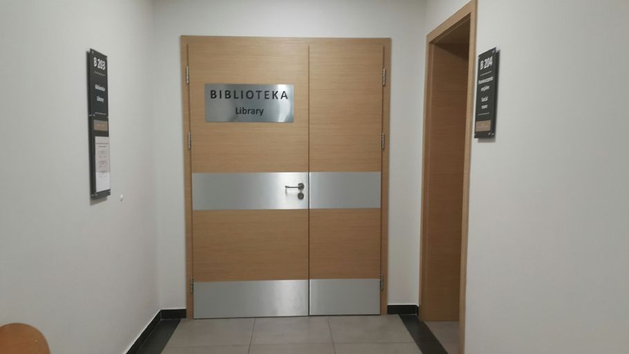 Zdjęcie zamkniętych drewnianych drzwi, ze srebrną tabliczką z napisem biblioteka.