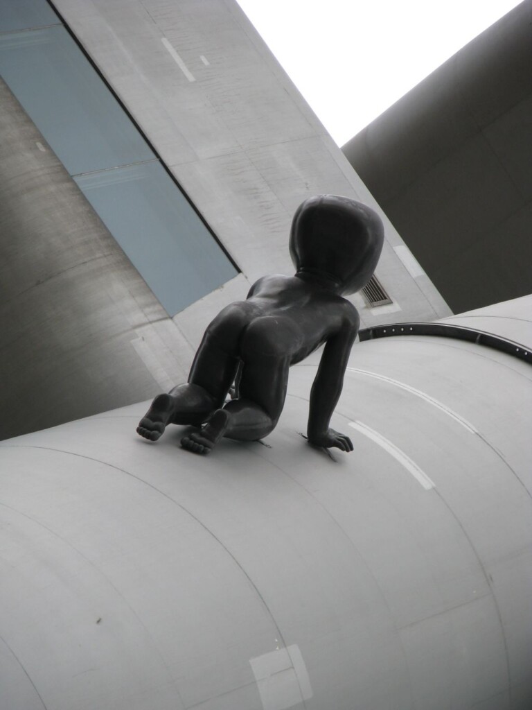 Zdjęcie instalacji artystycznej z rzeźbą dziecka na czworaka