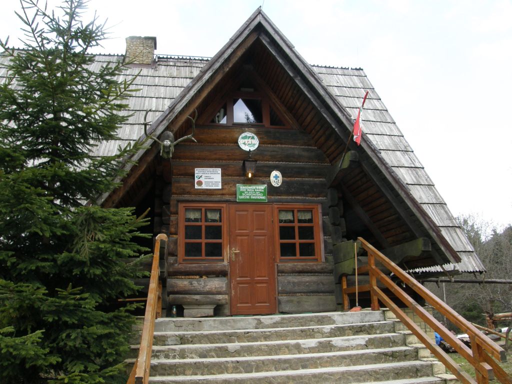 Zdjęcia wejścia do drewnianego budynku schroniska górskiego.