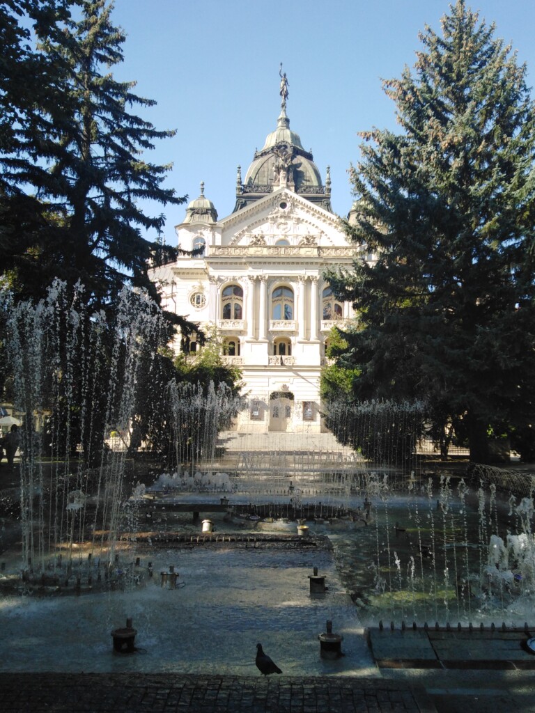 Zdjęcie, widok na biały budynek z kolumnami zwieńczony kopułą, na pierwszym planie fontanny