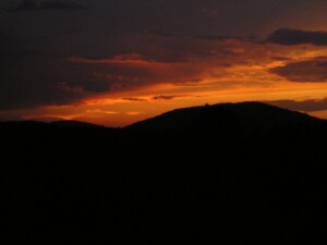 Zdjęcie wzgórz o zachodzi słońca, pomarańczowe niebo i tylko zarys gór