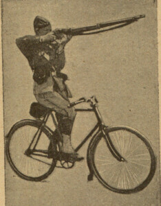człowiek jadący na rowerze i strzelający z karabinu.