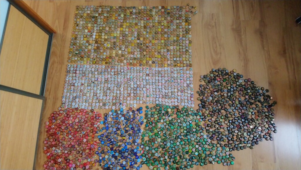 zdjęcie ogromnej ilości kapsli od piwa ułożonych kolorami na podłodze
