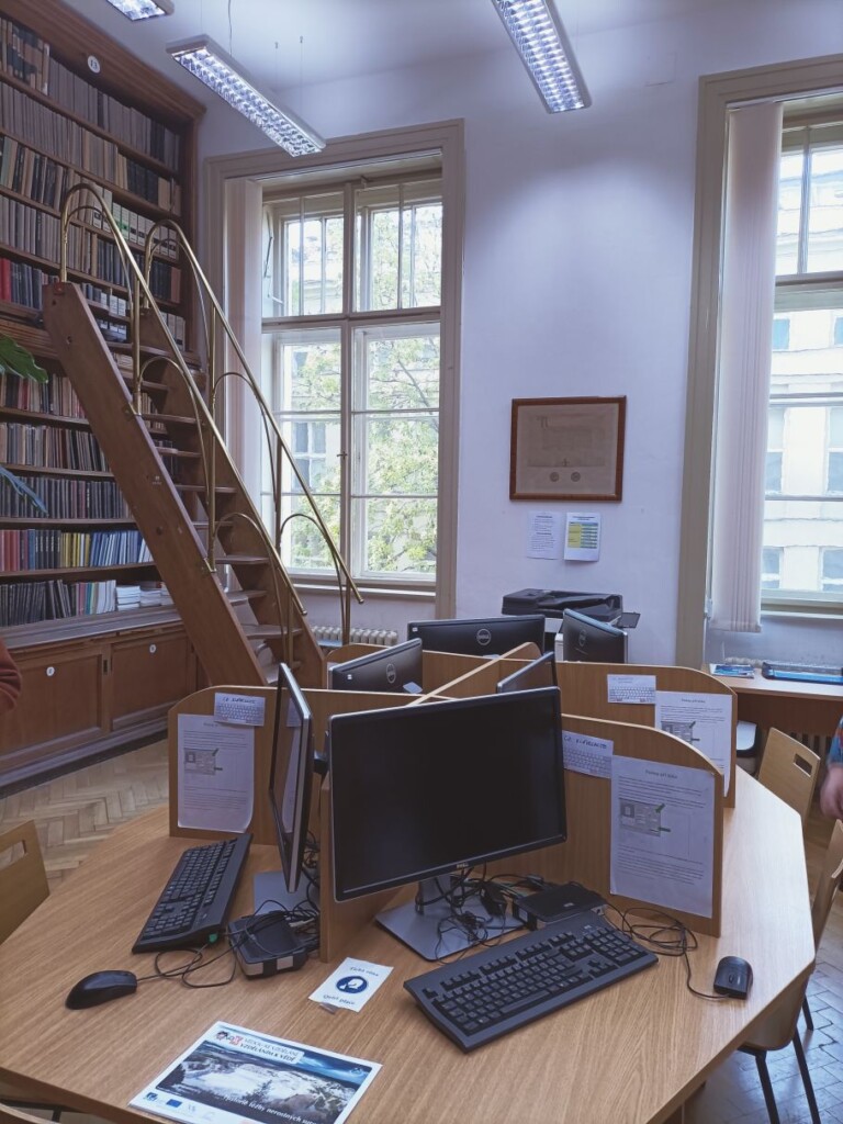 biurko z monitorami, w tle ozdobna drabina oparta o regał z książkami
