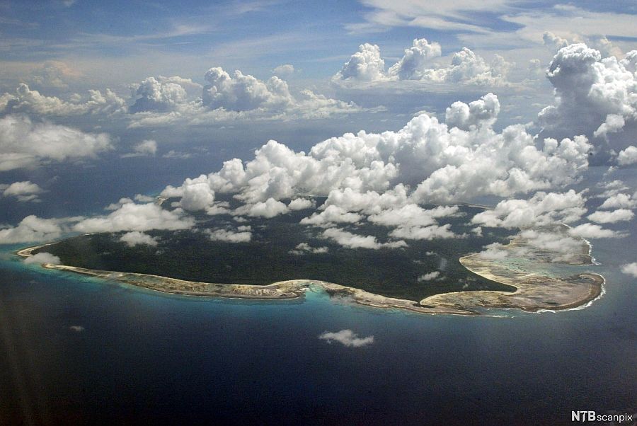 Zdjęcie lotnicze niewielkiej wyspy i unoszących się nad nią chmur.