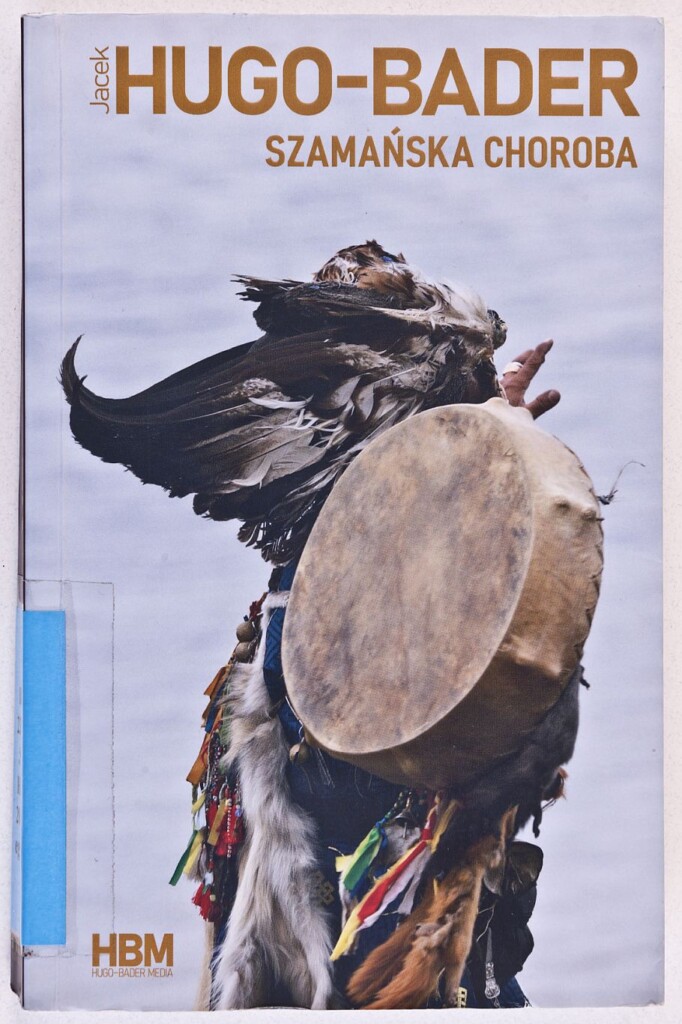 Okładka książki Szamańska choroba, na niej zdjęcia ubranego w pióra szaman w tańcu z rodzajem bębna.