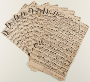 Strony z rękopisów ułożone w wachlarz zawierające zapis nutowy.
