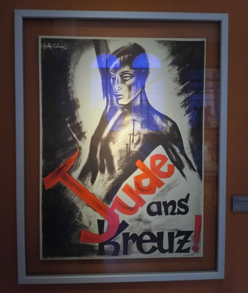 plakat przedstawiający tors nagiego mężczyzny podpisany "Jude ans Kreuz!"
