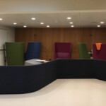 Zdjęcie przestrzeni bibliotecznej, w niej ustawione kolorowe, wysokie i wygodne fotele.