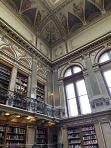 Zdjęcie wnętrza biblioteki, na nim antresola z regałami na książki, a na suficie bogate freski