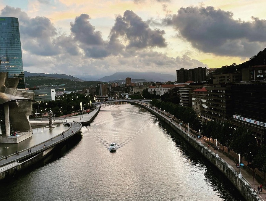 Zdjęcie panoramy miejskiej, na wprost rzeka, po lewej nowoczesne budynki, po prawej promenada i niższe, starsze budynki.