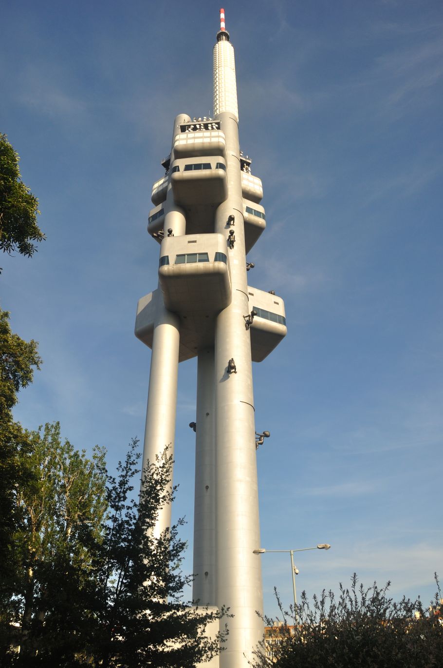 Zdjęcie wieży telewizyjnej w Pradze, trzy wielkie metalowe tuby pną się w niebo.