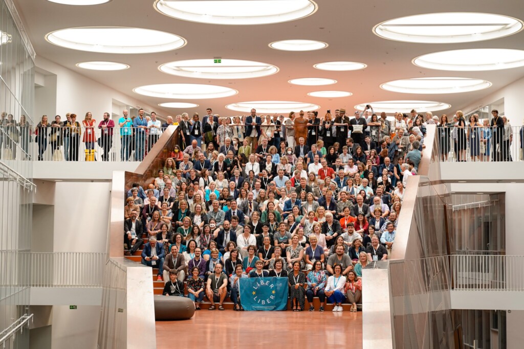 Zdjęcie grupowe uczestników konferencji siedzących na szerokich schodach.