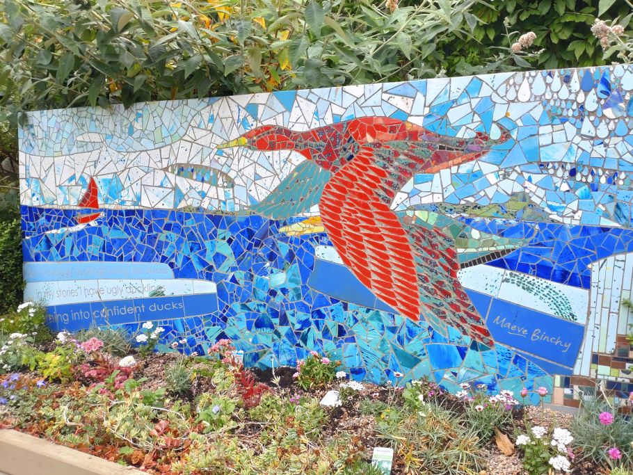 Mozaika na ścianie: czerwony ptak lecący nad niebieską wodą