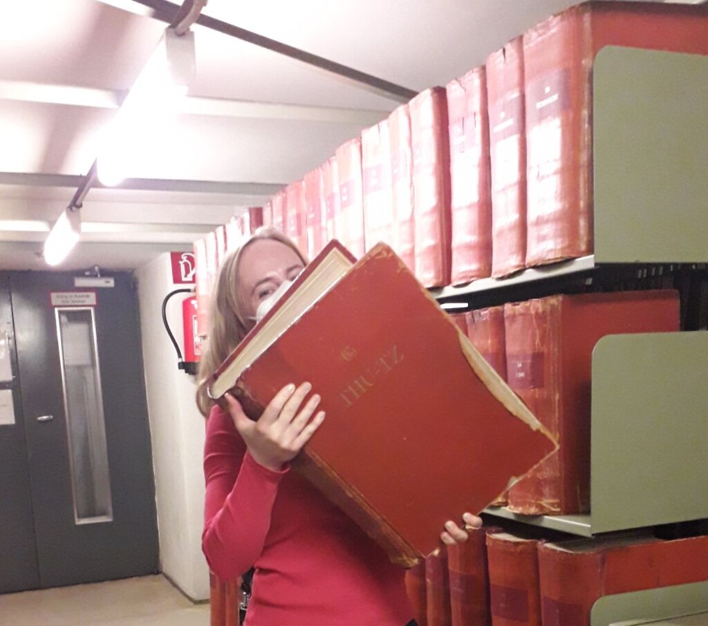 osoba dźwigająca bardzo grubą księgę w czerwonej oprawie