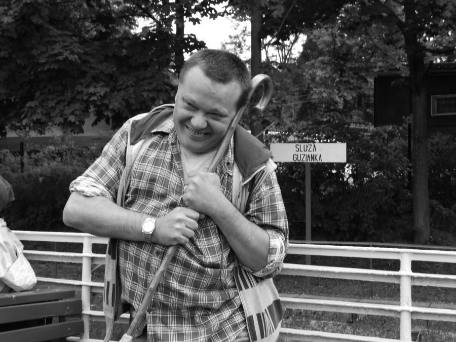 Zdjęcie mężczyzny przytulającego się z uśmiechem do laski inwalidzkiej.