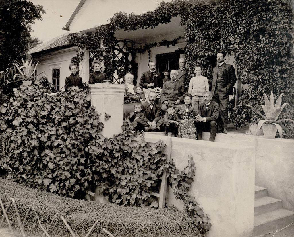 Stare zdjęcie rodzinne (grupowe). Ludzie stojący przed wejściem do domu.