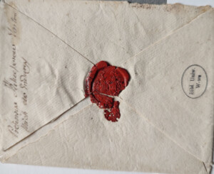 Koperta z odręczną notatką oraz czerwoną lakową pieczęcią, lekko przełamaną