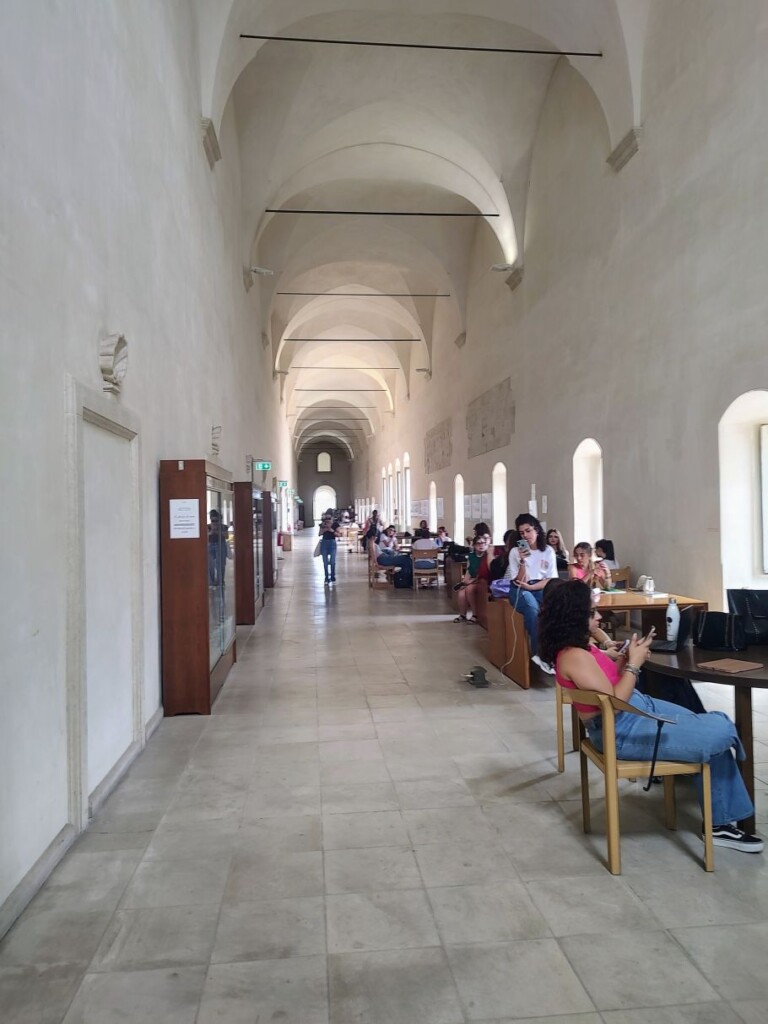 długi korytarz, przy stołach siedzą ludzie