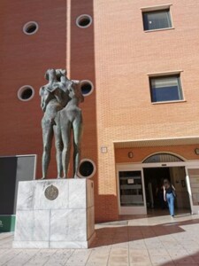 rzeźba dwojga nagich ludzi przed fasadą budynku z czerwonej cegły